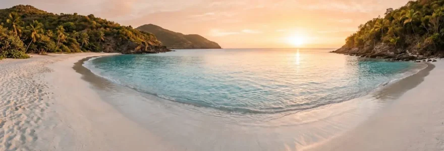 Vue panoramique de la plage de l'Anse des Flamands à Saint-Barthélémy au lever du soleil, avec sable blanc, eaux turquoise calmes et végétation tropicale préservée sur les collines